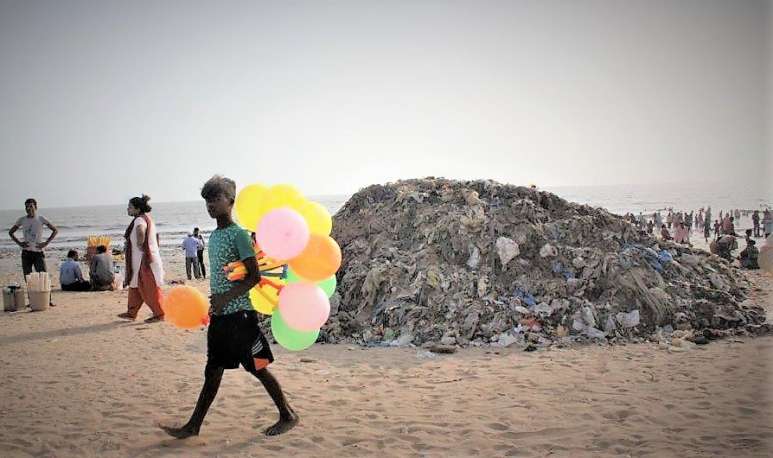 Hinter dem Ballonverkäufer ist ein riesiger Abfallberg am indischen Strand. Das sieht man leider in vielen Ländern.